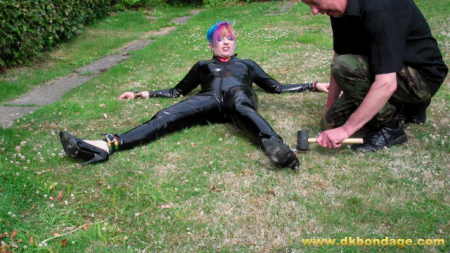 Mog Is Pegged Out In The Garden - Mog is looking stunning in her black, pvc, skin-tight catsuit and multi-coloured leather collar and cuffs.  We decide a sun-bathing session is what she needs and she agrees but we obviously did not agree how this was to be achieved.

mog is spreadeagled on the rear lawn of the garden using tent pegs.  We foolishly encourage her to escape thinking we have her pinned down.  Buy the clip to see what she does!

the final phase sees mog being double-pegged into the lawn with each peg driven deeply into the turf!

will she escape from this?