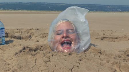Sand Bagged - Imagine coming across a cute **** on the beach up to her neck in sand. Well chaos happened to find herself buried in sand with a plastic bag on her head. The sun was scorching hot that day and the bag was really beginning to mist up as the air got thinner and thinner.