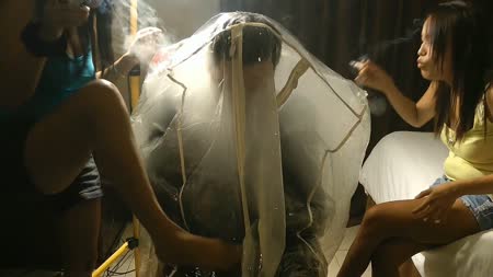 Smoke Dress Bag Chair - Slave is trapped in a latex sleepsack and zipped into the dress bag
as roxy and trixie are blowing their marlboro menthols into his air
supply filling up the bag with the combined second hand smoke of their
cigarettes.

runtime 5 min 5 sec